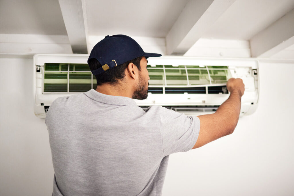 A technician repairs an air conditioning unit, focused on ensuring optimal performance and comfort in the environment.